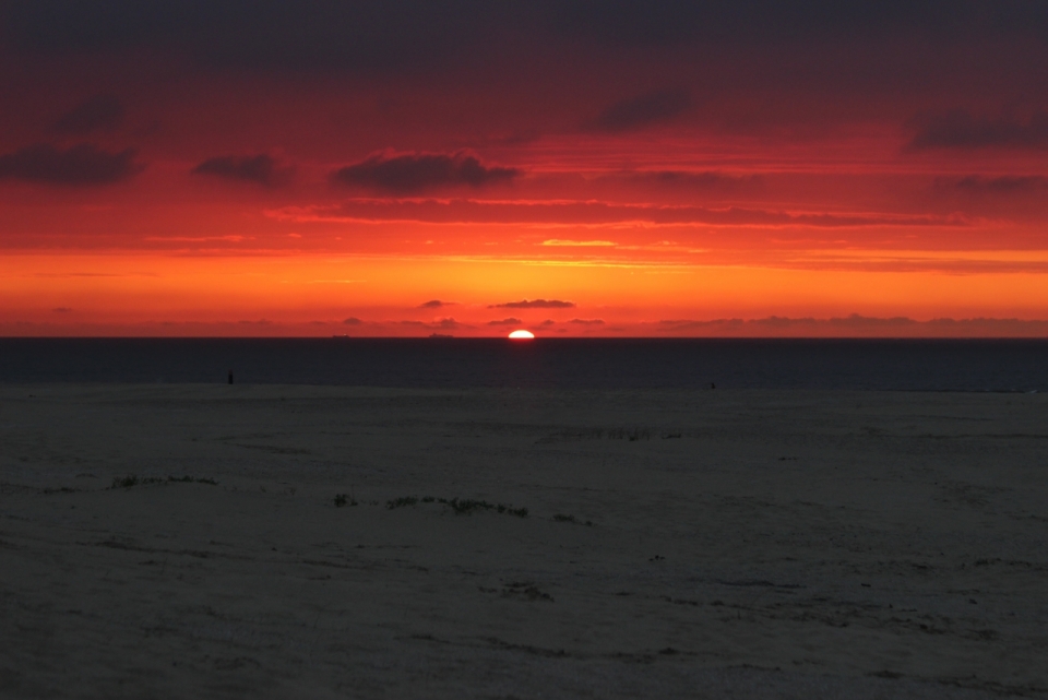 落日时分被染红的天空与大海边的沙滩