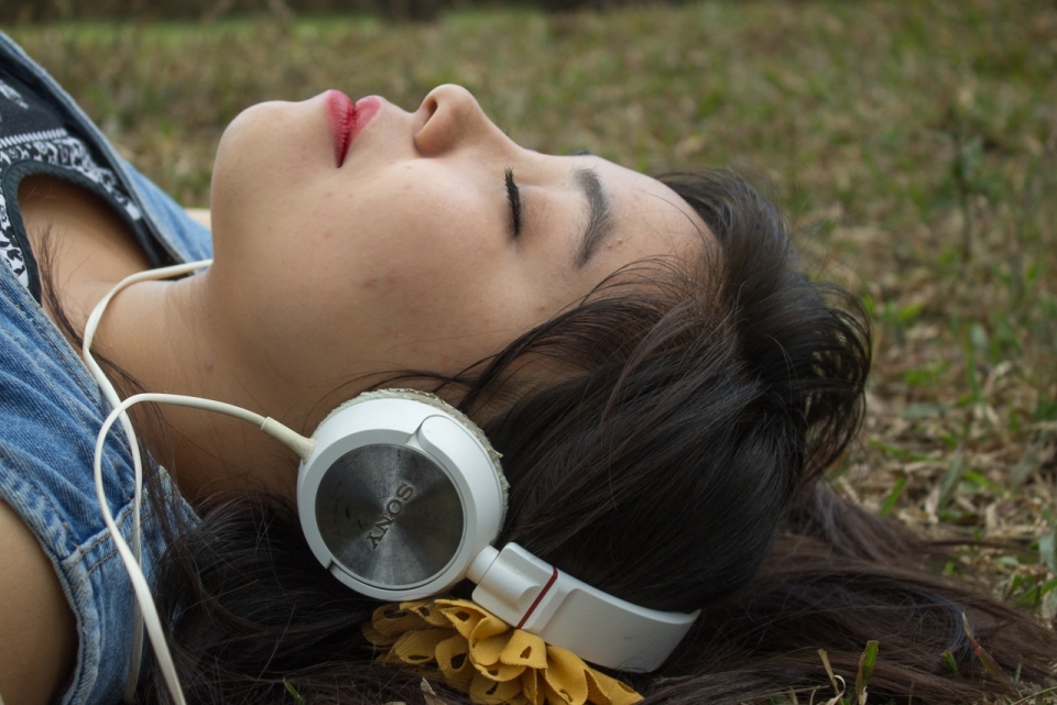 躺户外自然草坪戴头戴式耳机长发女性