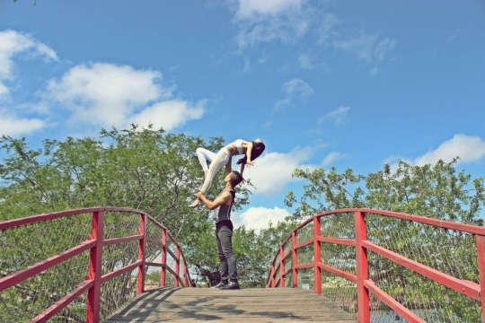 蓝天白云红色栏杆桥上表演的杂技演员