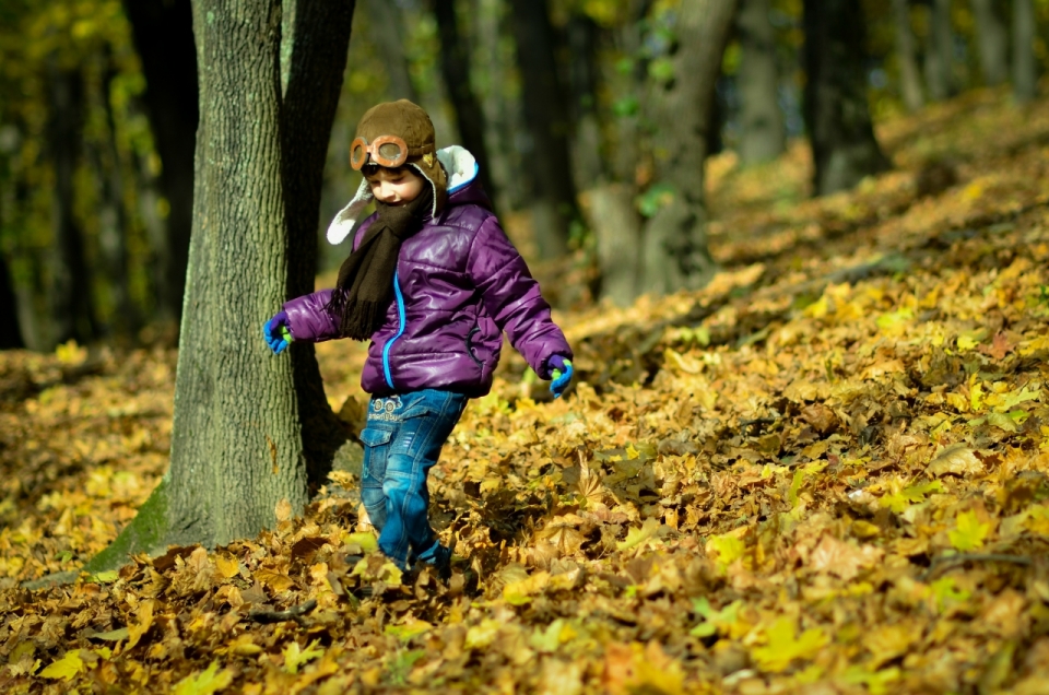 秋天在树林枯黄落叶堆上玩耍的男孩