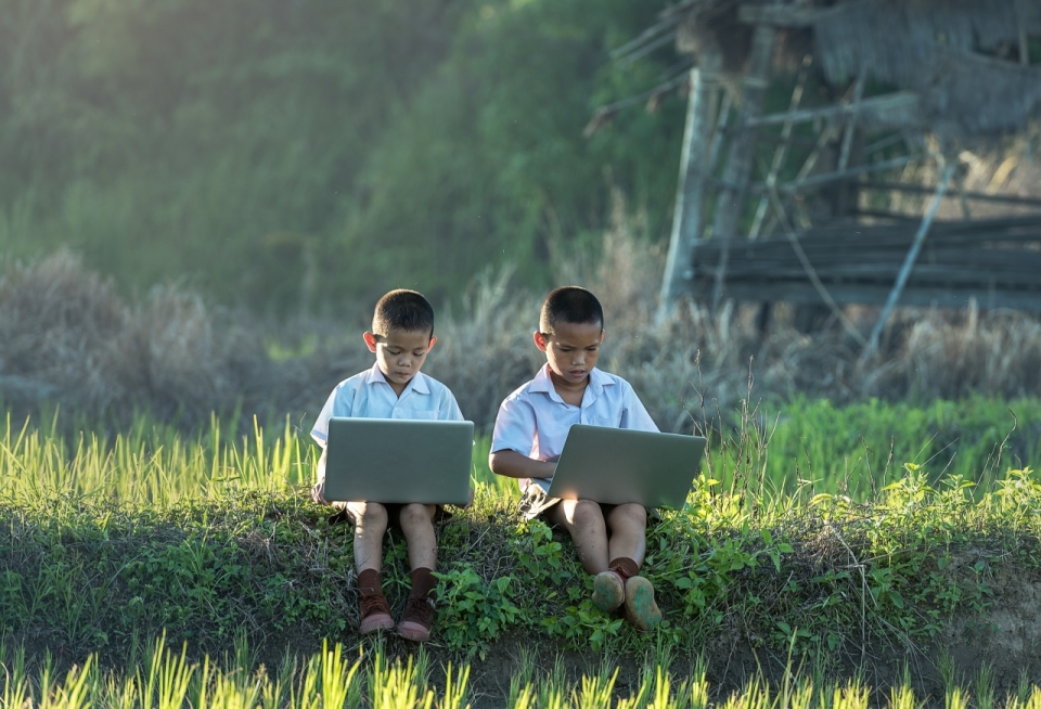 两个小男孩坐在草地上拿着画本画画