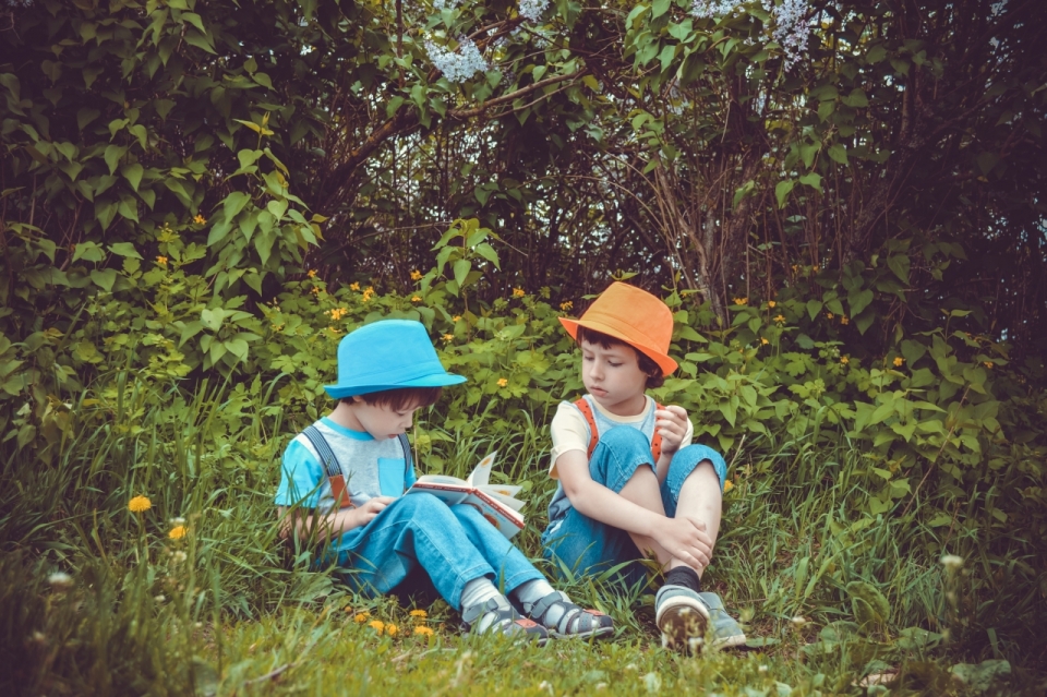坐森林自然绿色草坪戴彩色帽子可爱男孩