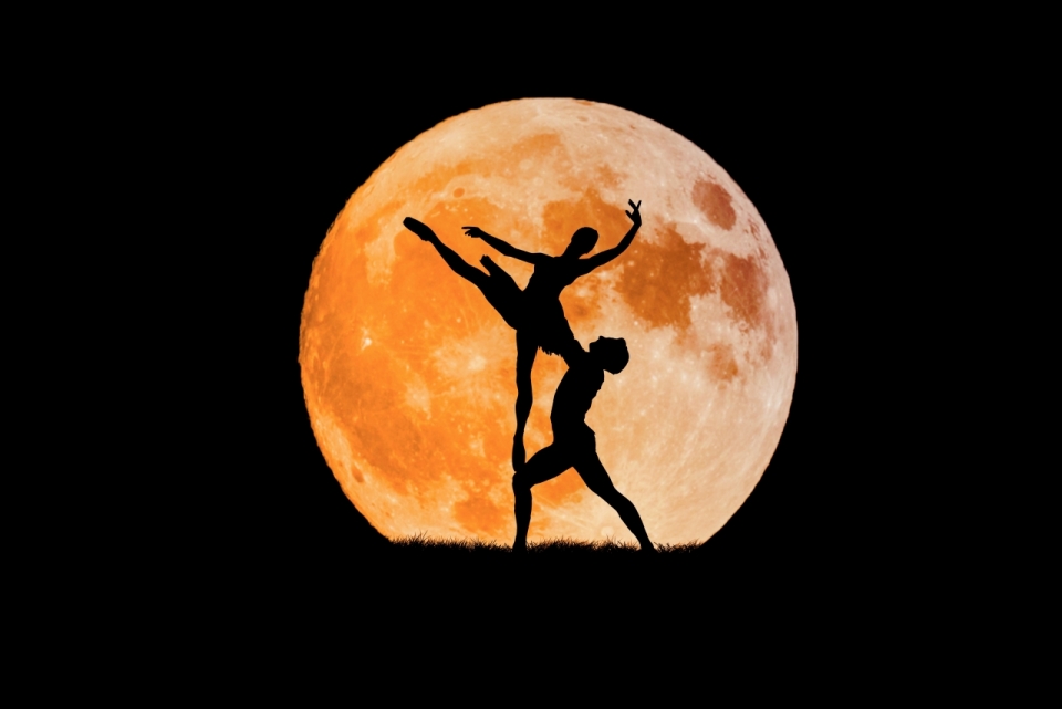 月亮下跳芭蕾舞的一对男女舞者剪影