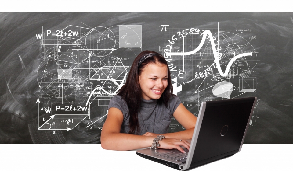 女孩在写满数学公式的黑板前用电脑学习