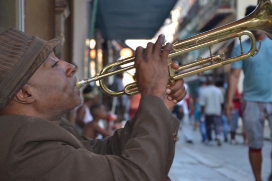 坐在路边演奏小号的黑人男子