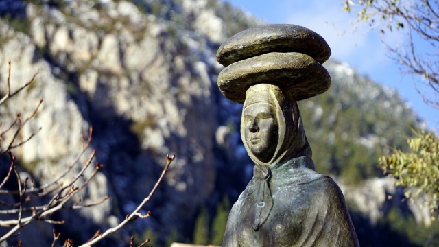 高山下头顶顶着两块石头的人石雕摄影