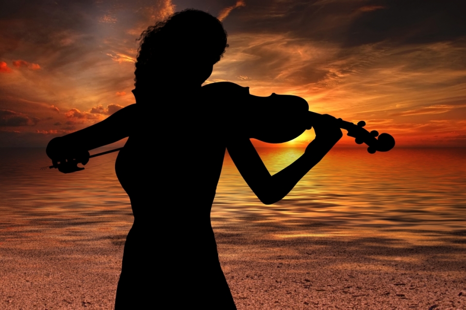 黄昏海岸边拉小提琴黑色女性剪影