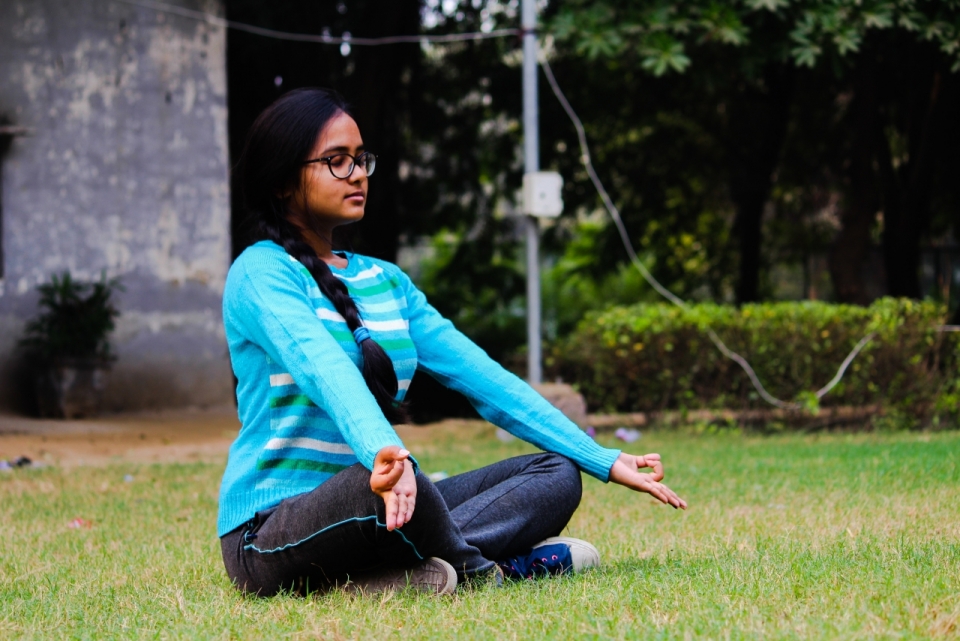 穿着运动装正在草坪上打坐的印度少女