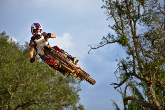 树林间飞驰行驶摩托车手人物特写