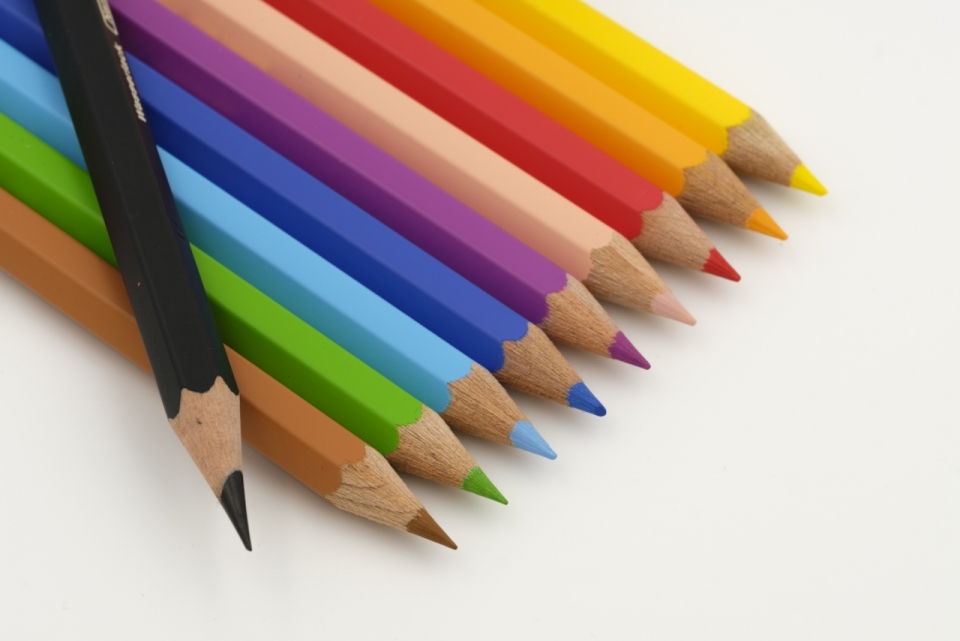 白色桌面上整齐摆放的彩色画笔