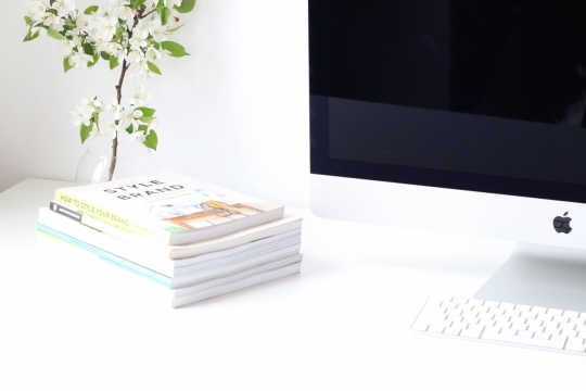简约画面白色电脑桌上苹果电脑一体机和几本摞起来的书