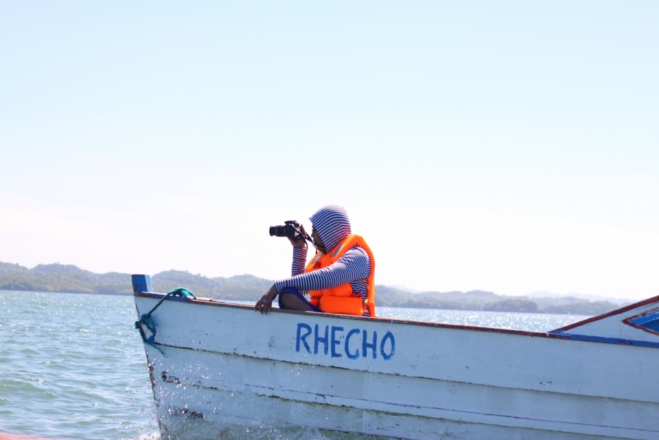 大海上坐在船头穿着救生衣的摄影师