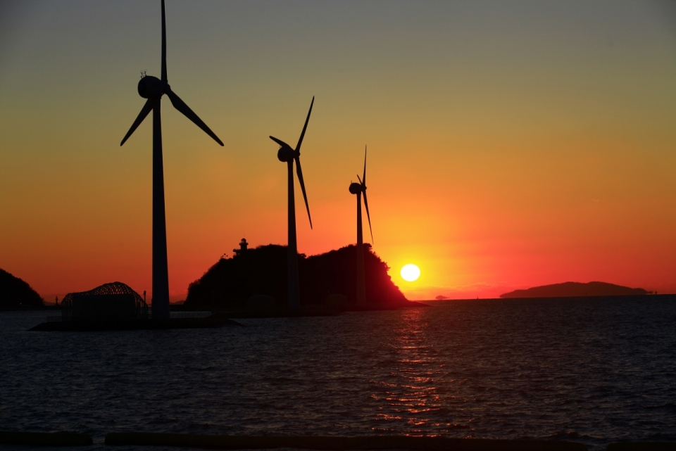 夕阳下大海边的风力发电站摄影
