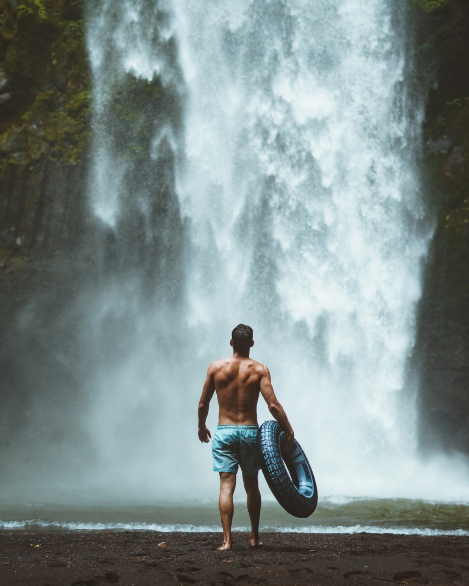 户外自然瀑布前拿游泳圈短发健壮男性