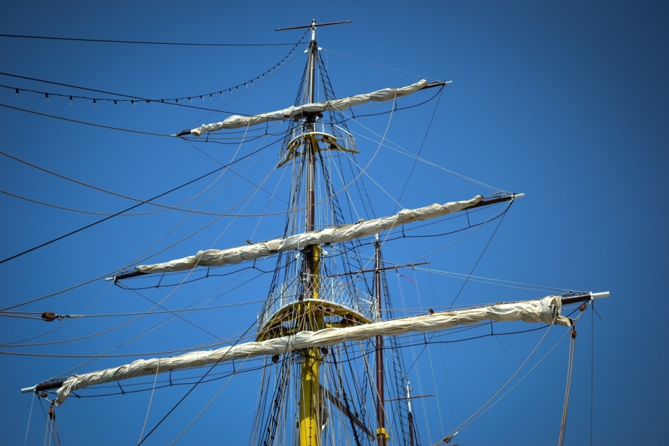 蔚蓝天空下帆船上连着许多绳索的桅杆