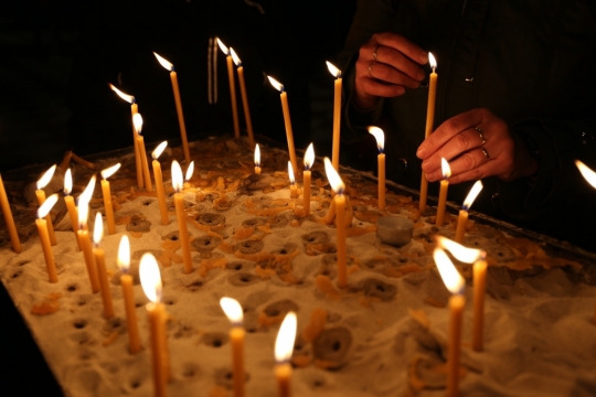 黑暗处在出台上点蜡烛的人手部和烛台摄影