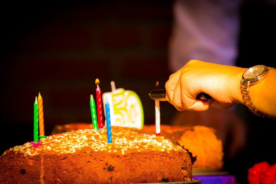 昏暗室内点燃生日蛋糕上彩色蜡烛庆祝
