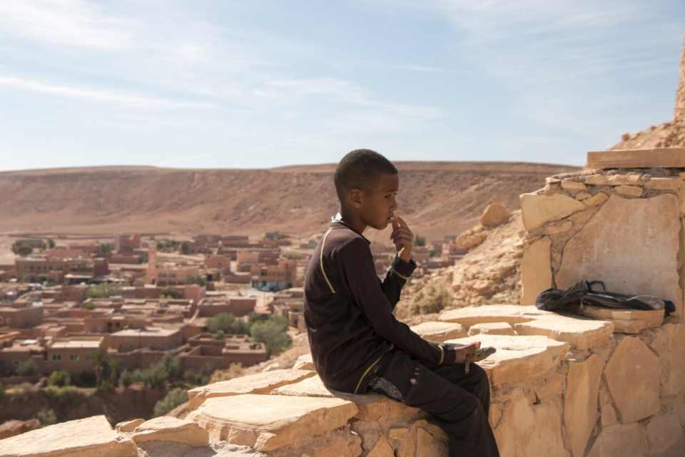 贫困地区的非洲男孩坐在石头围墙上