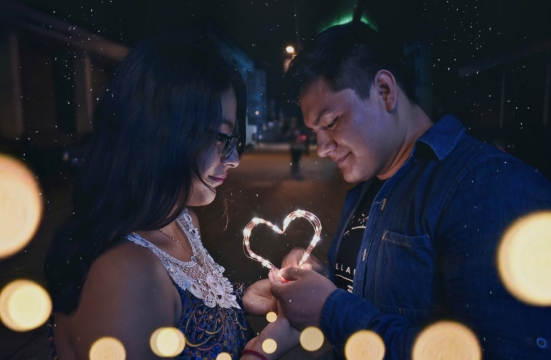 夜晚城市街道拿浪漫心形灯饰情侣