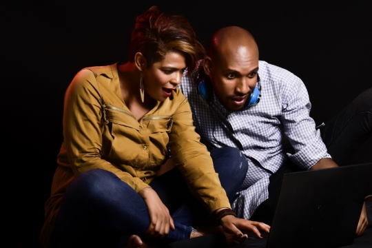 黑色背景挂头戴式耳机男性女性看笔记本电脑