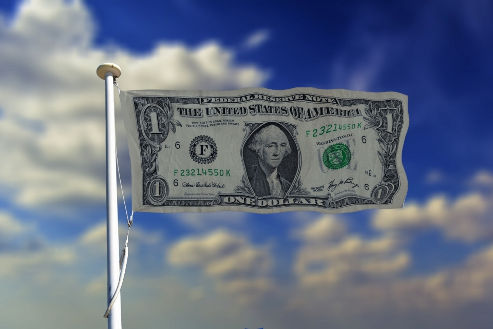 蓝天白云背景下旗杆上挂着美元钞票旗帜