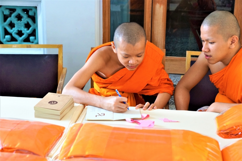 寺庙室内年轻僧侣笔在白色桌面本子书写