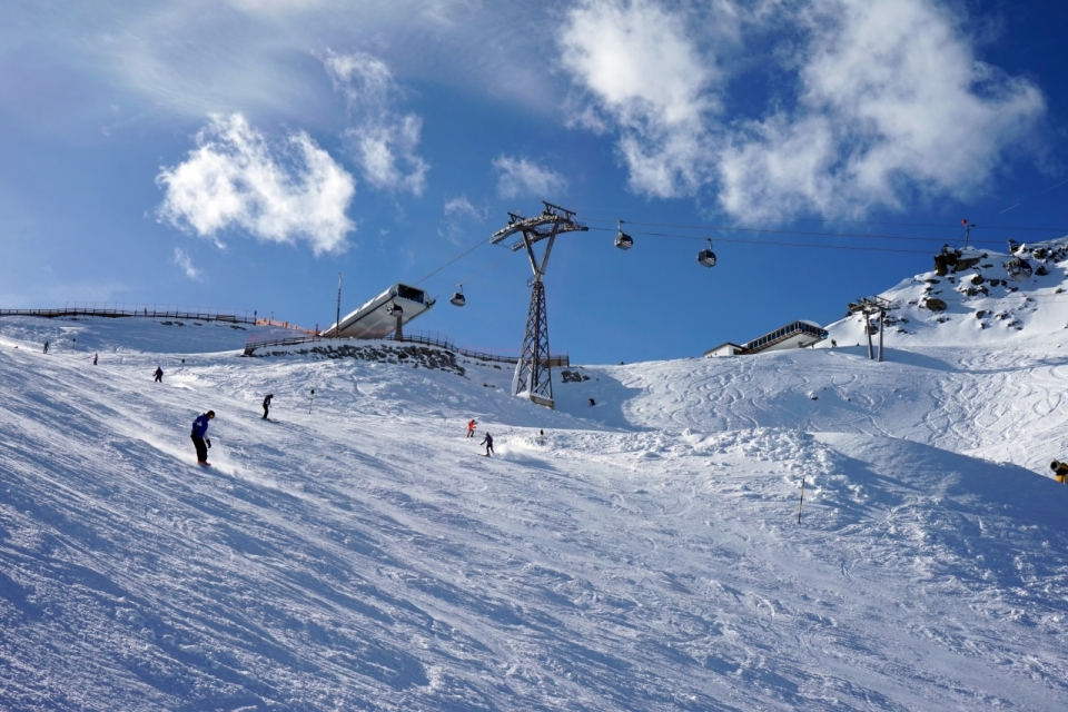 美丽蓝天下雪山上游客众多的滑雪场