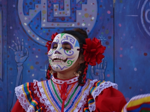 穿亡灵节鲜艳装扮戴面具女性舞者