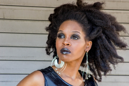 白色墙壁前戴夸张耳饰时尚长发黑人女性