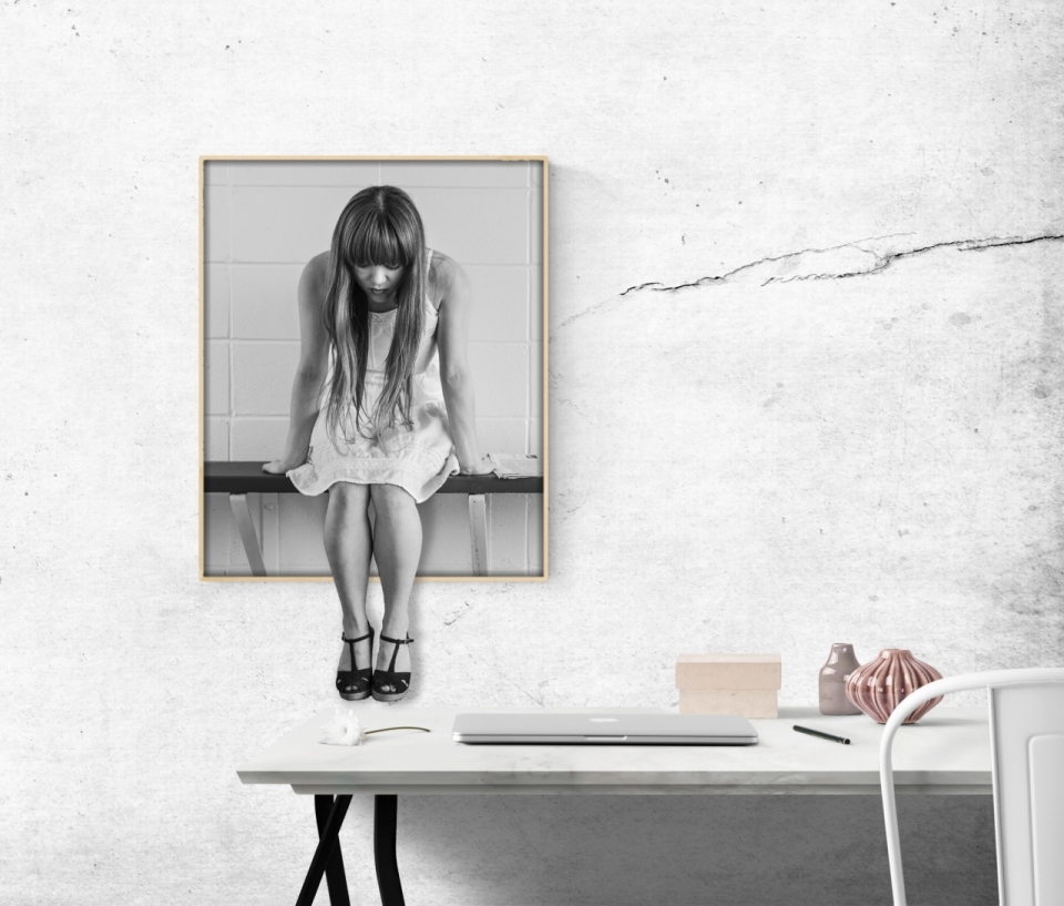 裂痕白色墙面上画框中长裙女人坐在黑色桌子上
