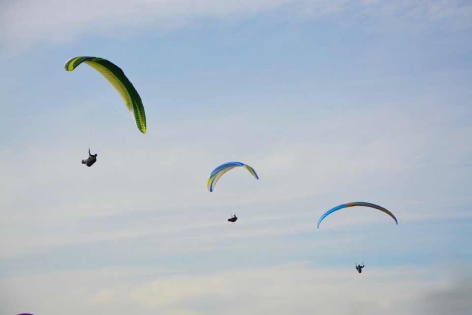 三个在天空上的开着降落伞滑行的人