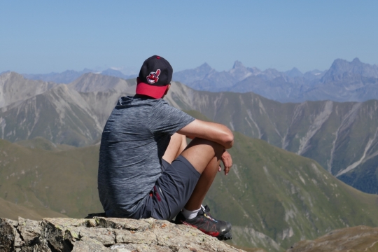 登山者蹲坐悬崖边短袖清凉着装特写