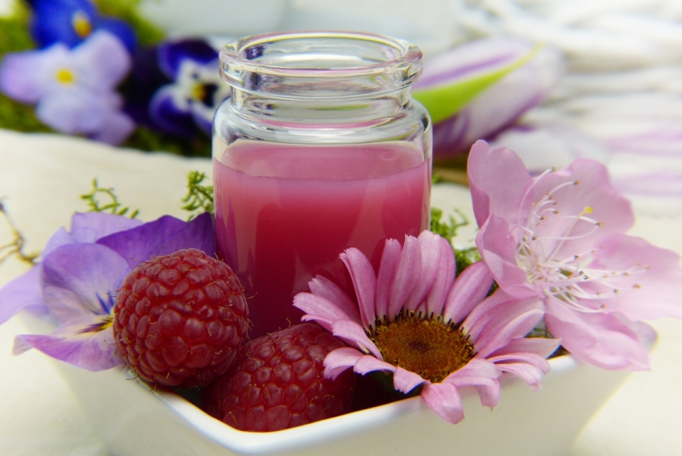 室内白色桌面盘子中花朵树莓玻璃瓶果汁