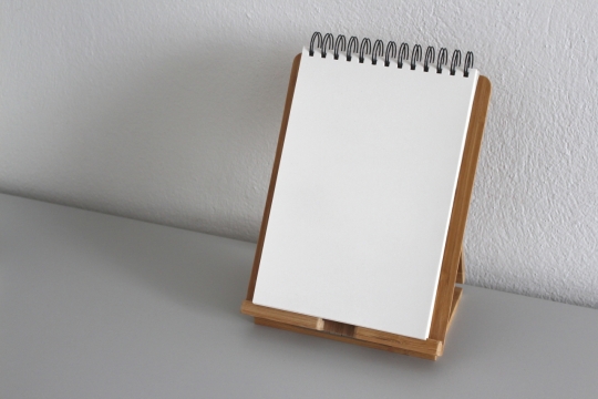 室内墙壁白色桌面上托架空白线圈素描本