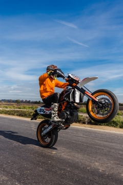 蓝天白云道路上翘起摩托车的特技车手