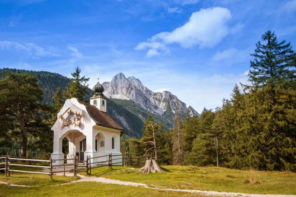 蓝天下的山脉和树林草地白色小屋子风光