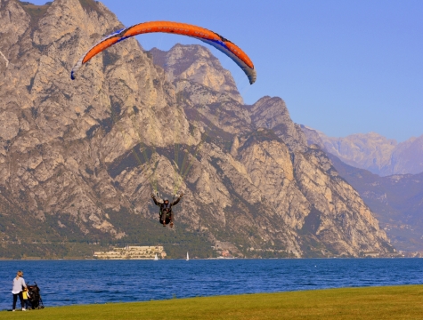 在蓝色水边草地上跳伞降落的人