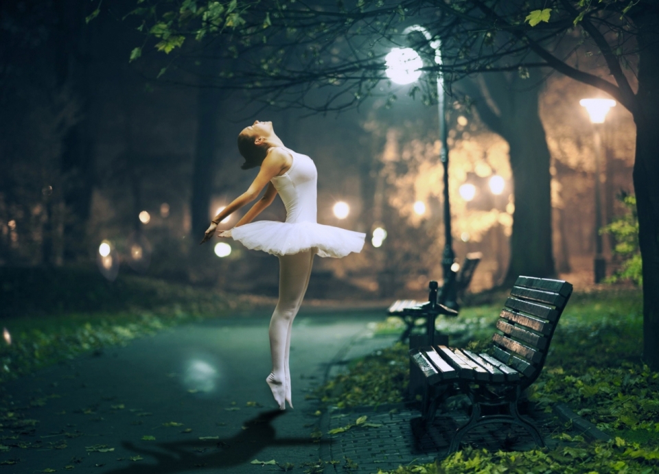 夜晚路灯下长凳旁跳舞的芭蕾舞者