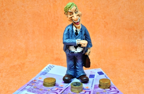 橙色背景站纸币硬币上彩色男性玩具模型