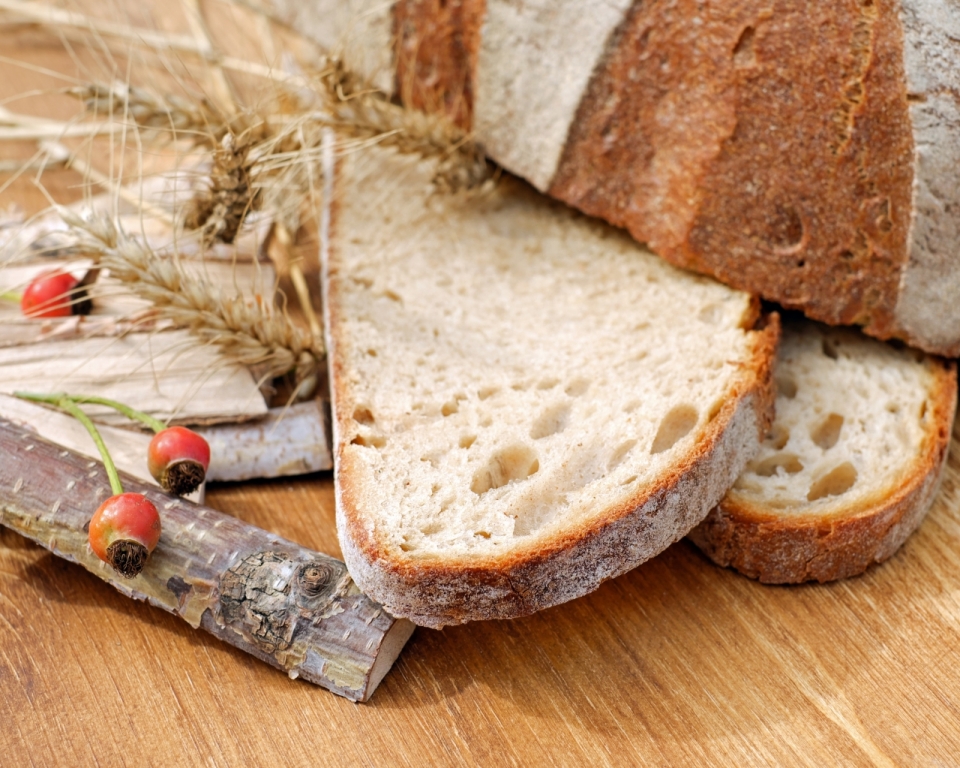 木桌上放的小麦和切片的面包食物摄影