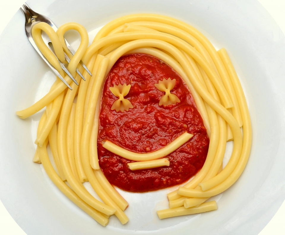 盘子里摆出笑脸的意大利面和番茄酱美食摄影