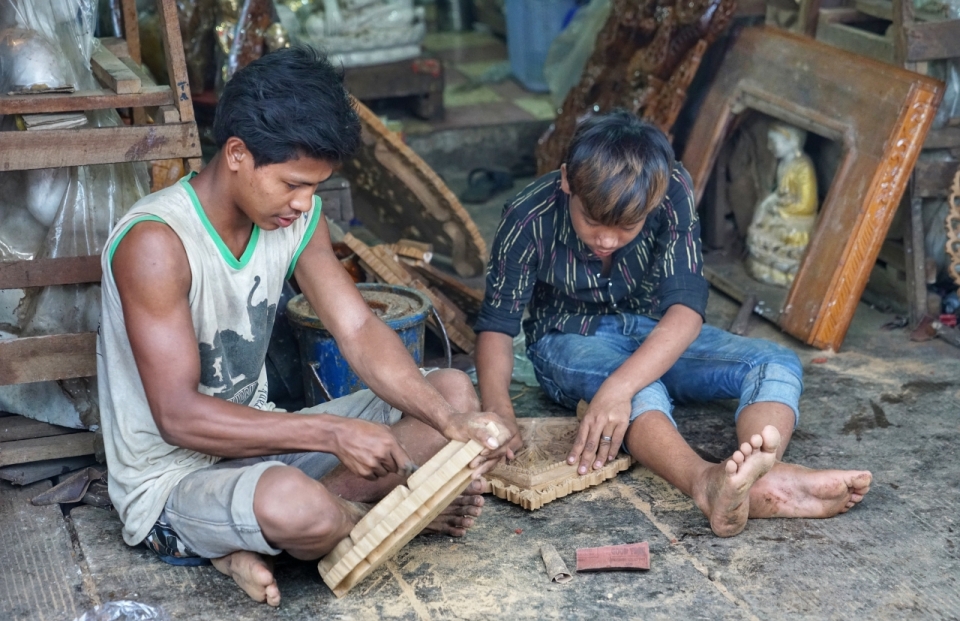 两个小男孩坐在地板山雕刻木头艺术品