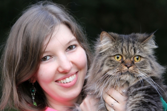 黑色背景抱可爱宠物猫长发女性