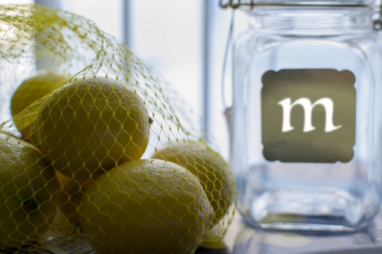 室内桌面透明玻璃瓶旁黄色新鲜柠檬