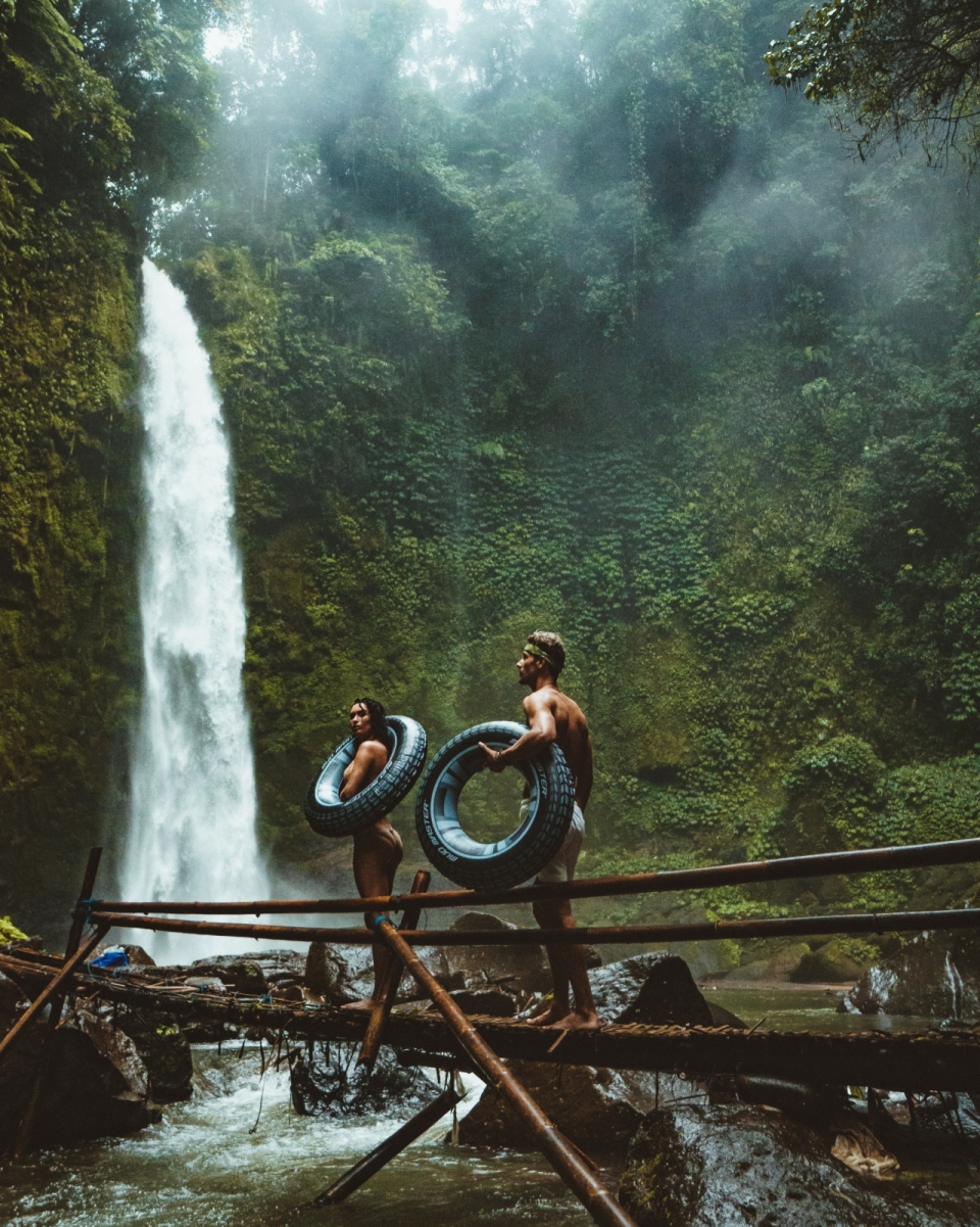 山峰自然瀑布前抱黑色轮胎泳装男女