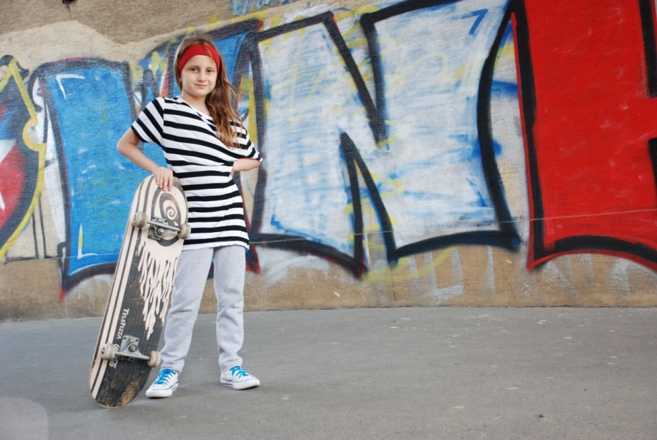 城市街头喷绘涂鸦墙壁前滑板长发女孩