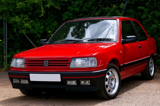 乡间公路上一辆红色的东风标致老式轿车