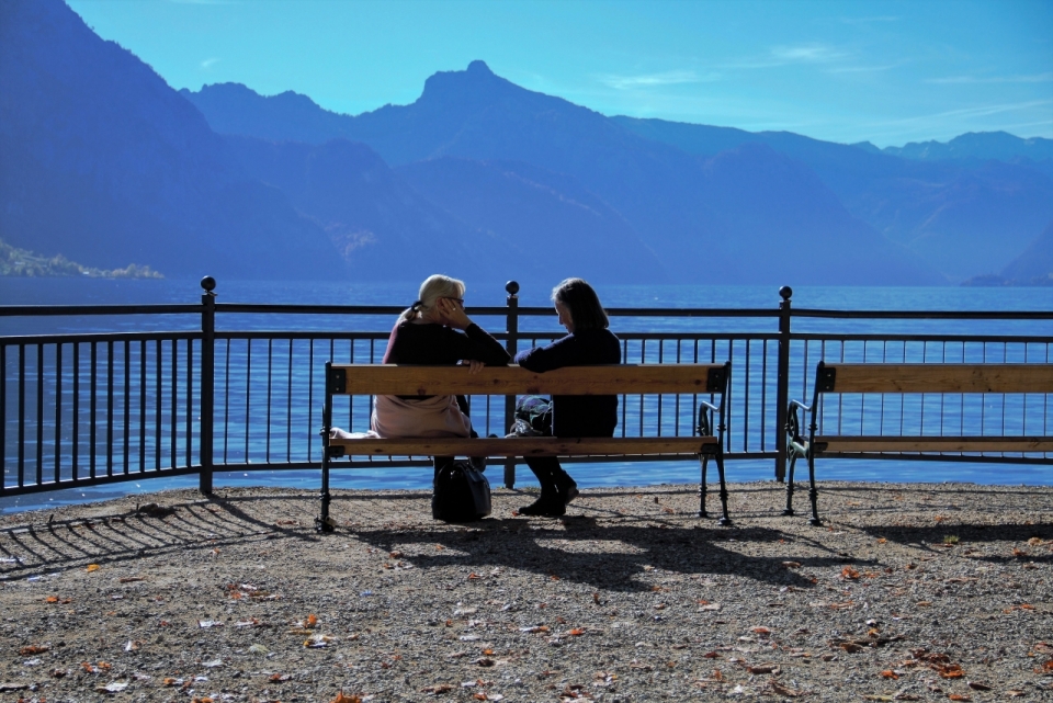坐在湖泊观景台木椅上的两个女人