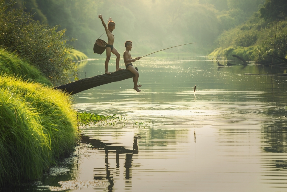 两个小男孩在环境优美的河边钓鱼
