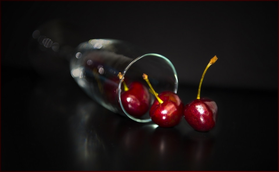黑色背景玻璃杯子中新鲜红色樱桃水果